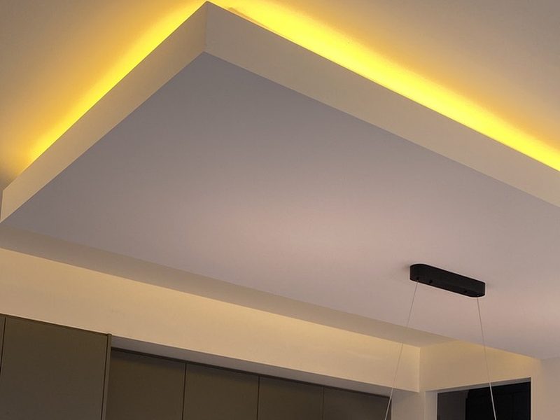 Modern kitchen with curved LED pendant light and warm cove lighting
