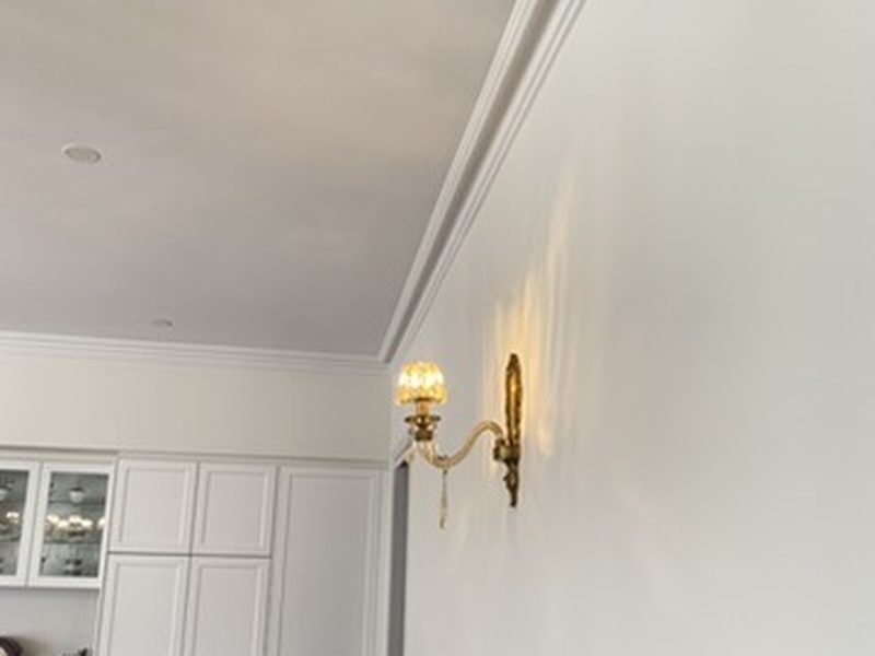 Brass wall sconce installed against classic cornice and panelling in a luxury Adelaide hallway