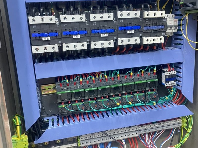 Inside of a residential switchboard with DIN-rail breakers, terminal blocks and clearly colour-coded wiring